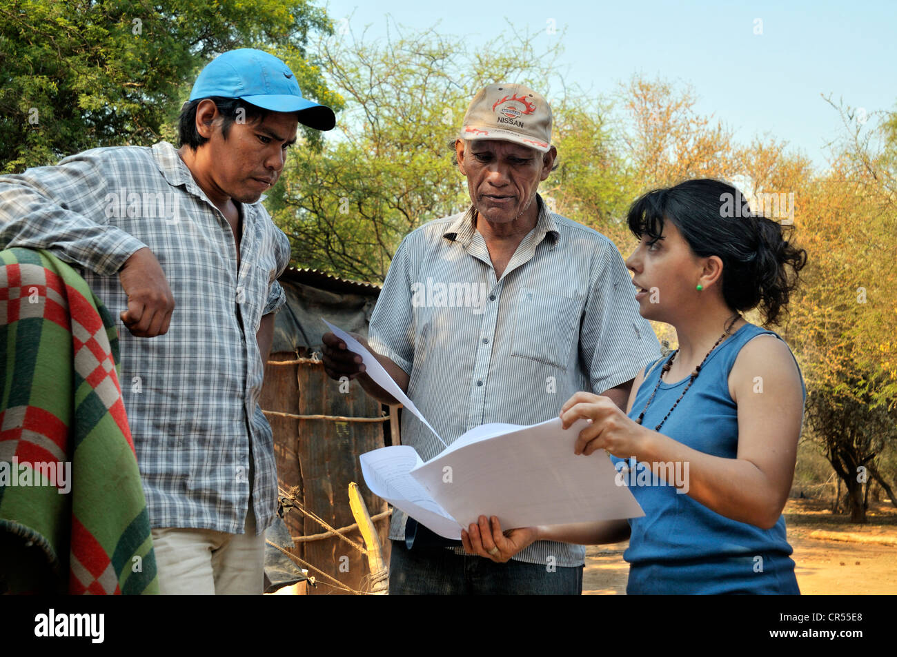 Landraub, Beratung, Entwicklungshelferin Dokumente mit einem Cacique, Gemeindevorsteher und seinem Sohn diskutieren, brauchen sie diese Stockfoto