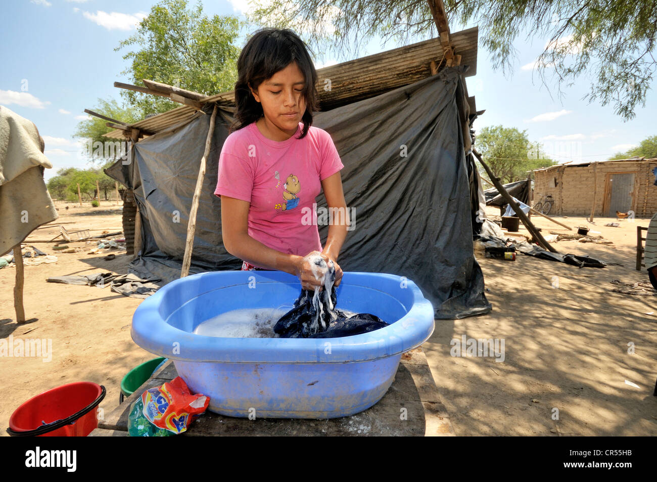 Junge Frau, 18 Jahre, mit indigenen Funktionen Waschen Wäsche vor ihrer Hütte aus Plastikplanen Stockfoto