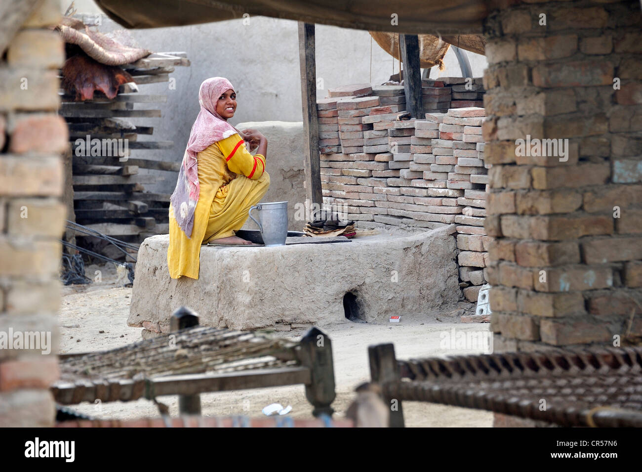 Junge Frau sitzt durch einen Ofen zum Backen von Brot, Basti Lehar Walla Dorf, Punjab, Pakistan, Asien Stockfoto