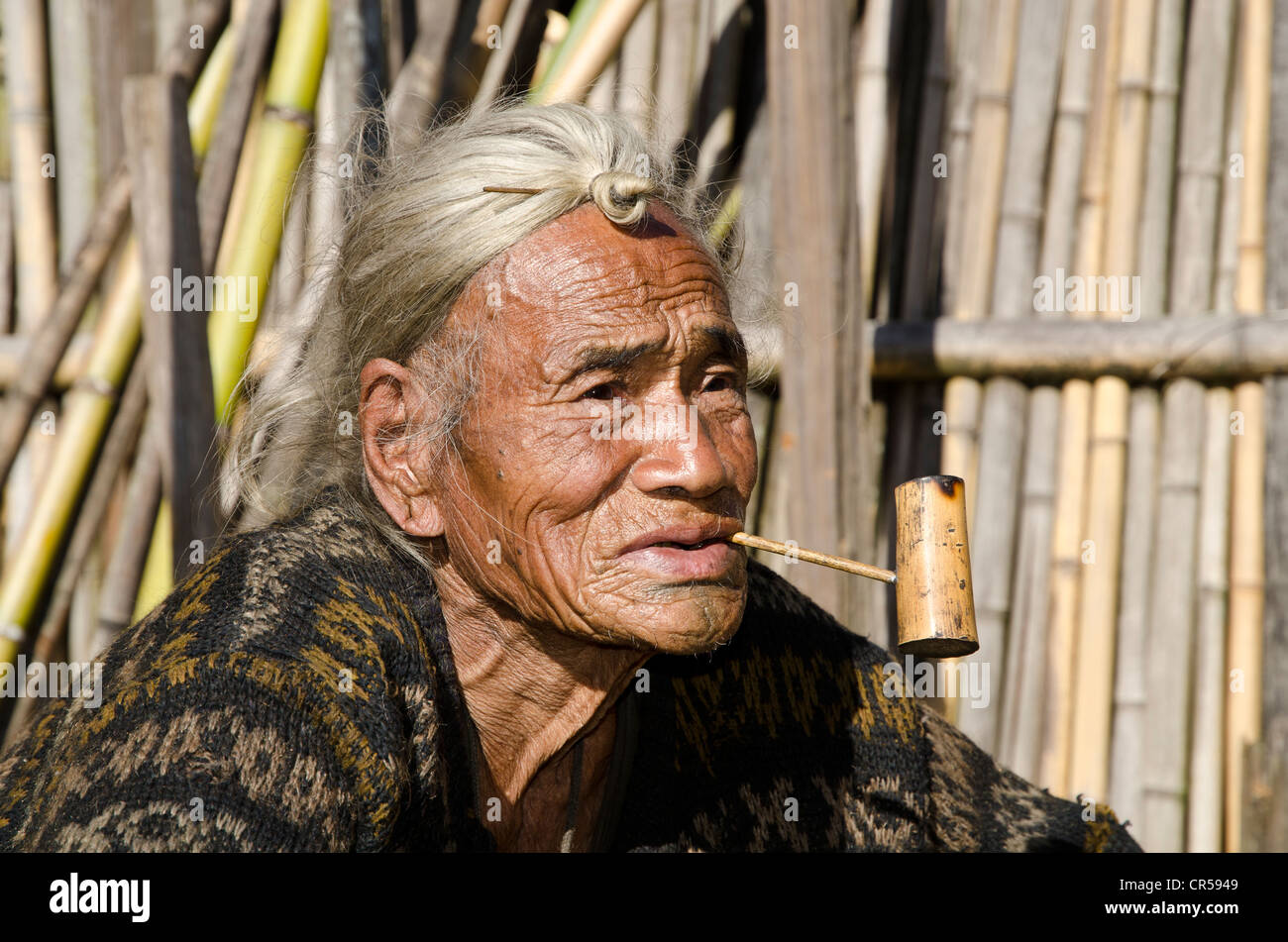 Apatani Greis mit den typischen Haaren Knoten an der Stirn, vor seinem Haus Hong Dorf, Arunachal Pradesh, Indien, Asien Stockfoto