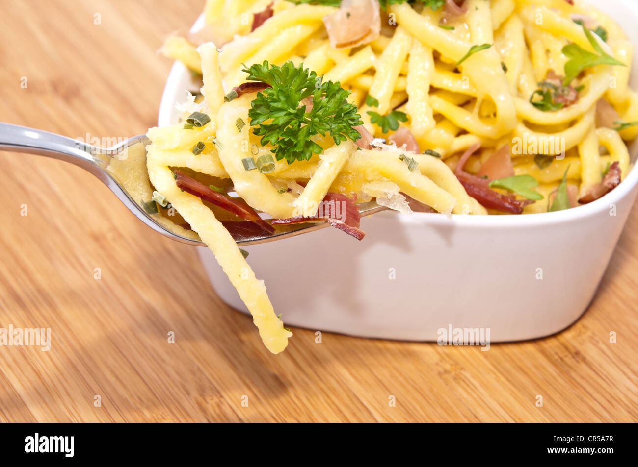 Käse-Spätzle mit Anteil an Gabel auf hölzernen Hintergrund Stockfoto