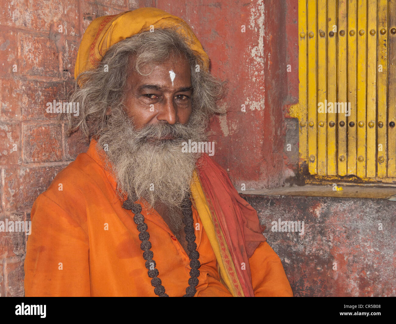 Ein Sadhu, heiliger Mann von Indien, sitzt vor einem kleinen Schrein in den Straßen von New Delhi Stockfoto
