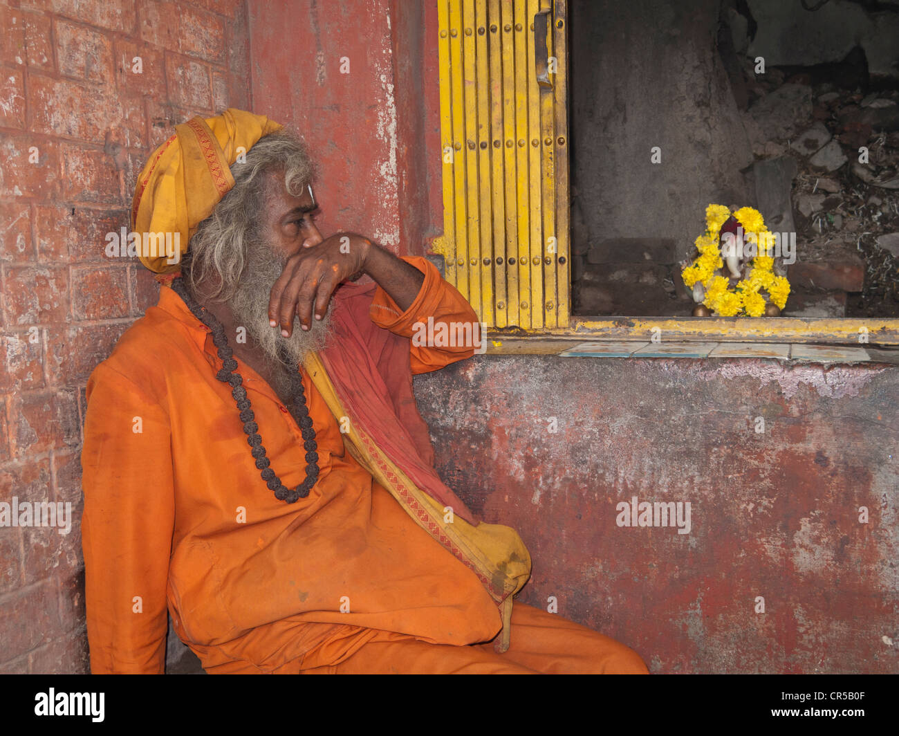 Ein Sadhu, heiliger Mann von Indien, sitzt vor einem kleinen Schrein in den Straßen von New Delhi, Neu Delhi, Indien, Asien Stockfoto