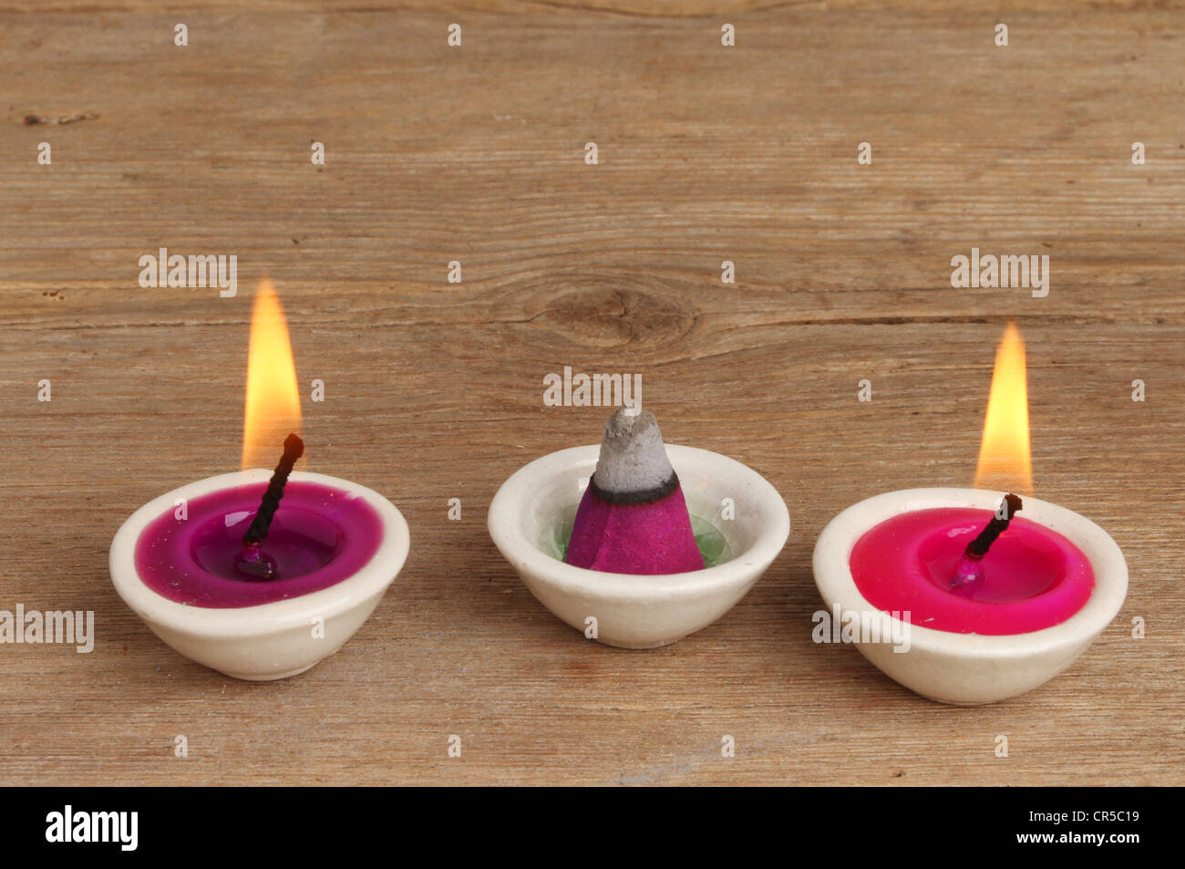 Kleine duftende brennende Kerzen und Weihrauch auf einem Hintergrund von verwittertem Holz Stockfoto