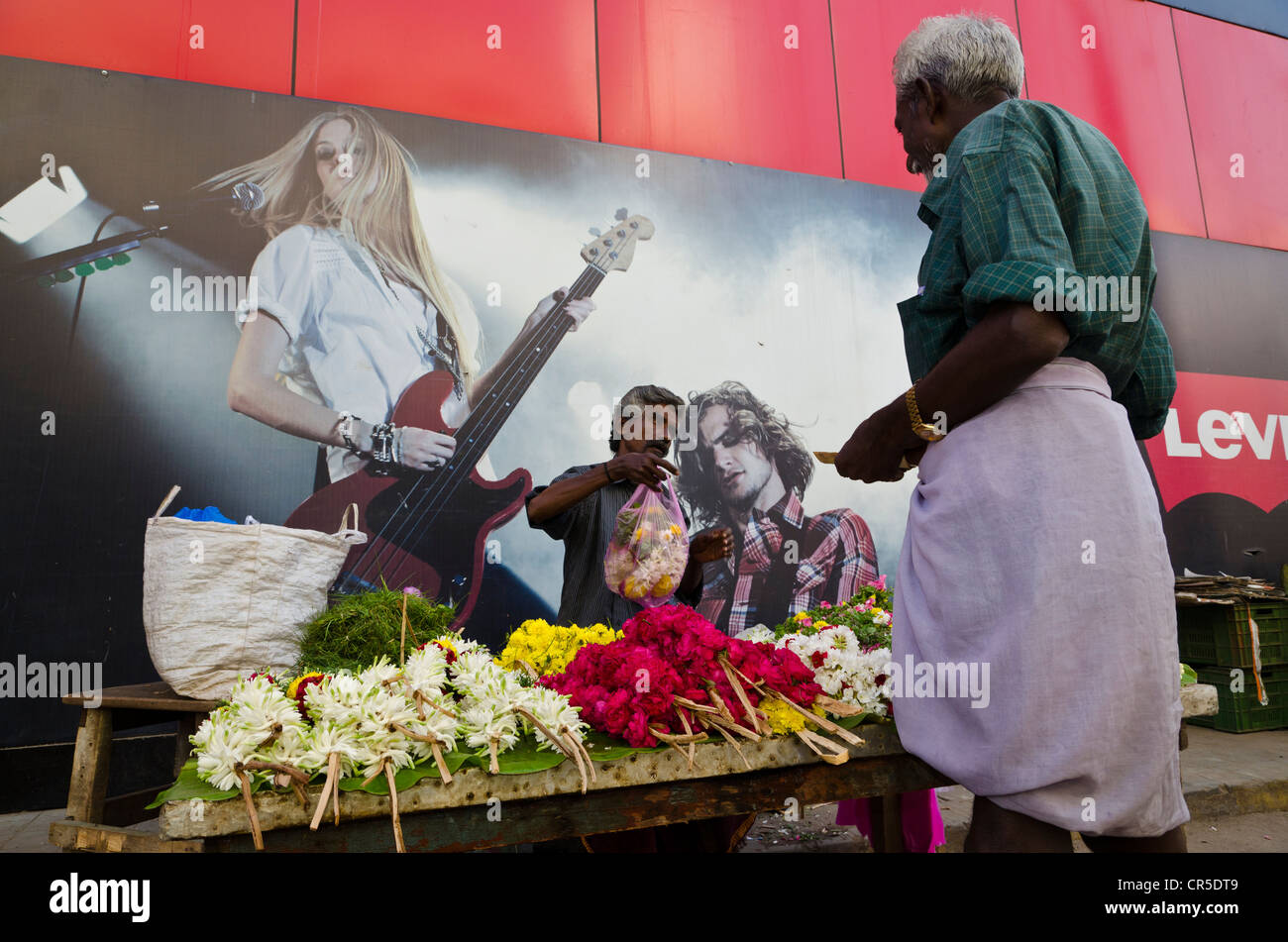 Flowerseller mit seinem Shop richten Sie vor dem Konzertplakat, Madurai, Tamil Nadu, Indien, Asien Stockfoto