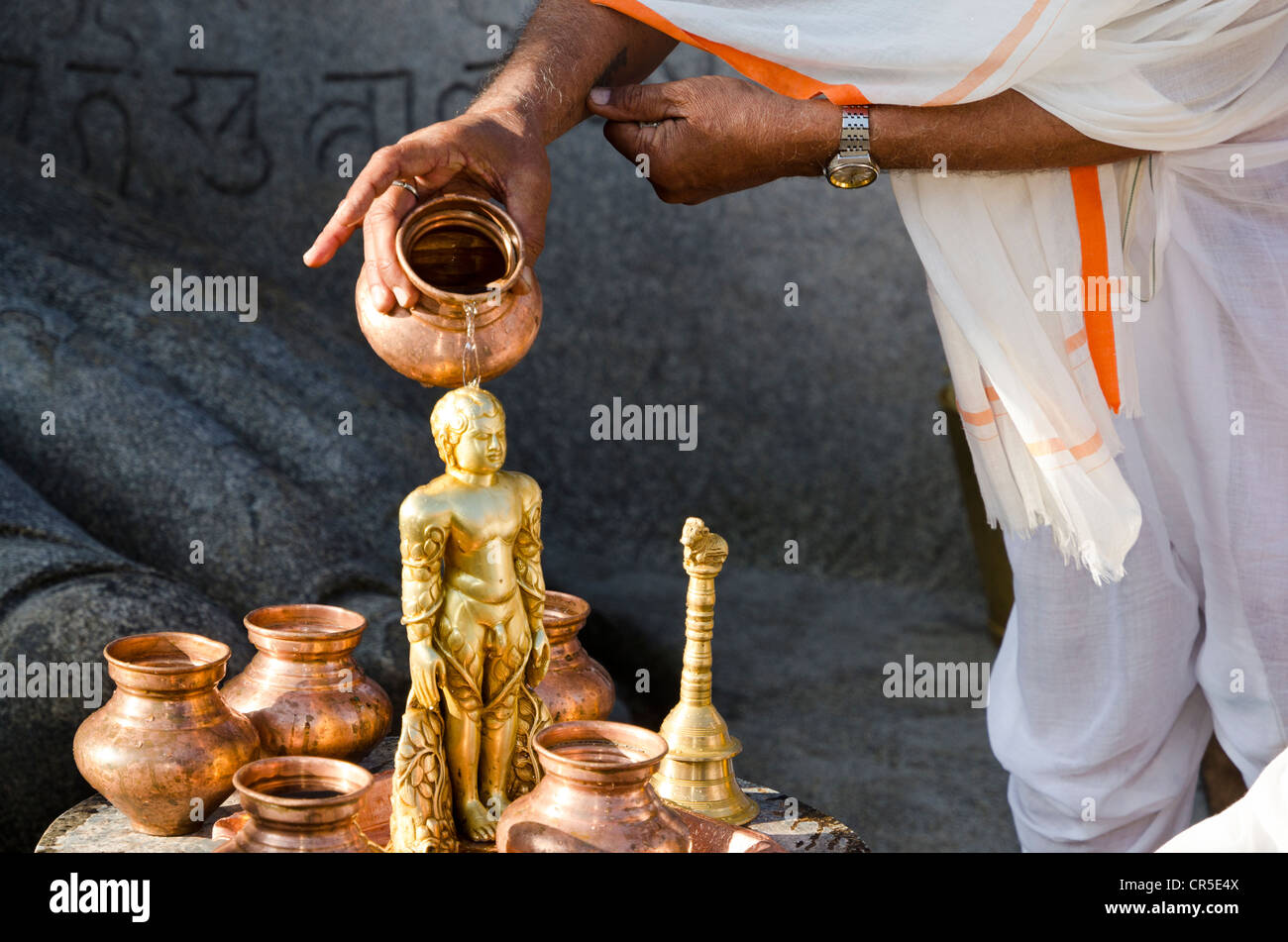 Jain Pilger gießt Wasser auf die kleine Statue am Fuße der gigantischen Statue von Gomateshwara in Indien, Asien Stockfoto