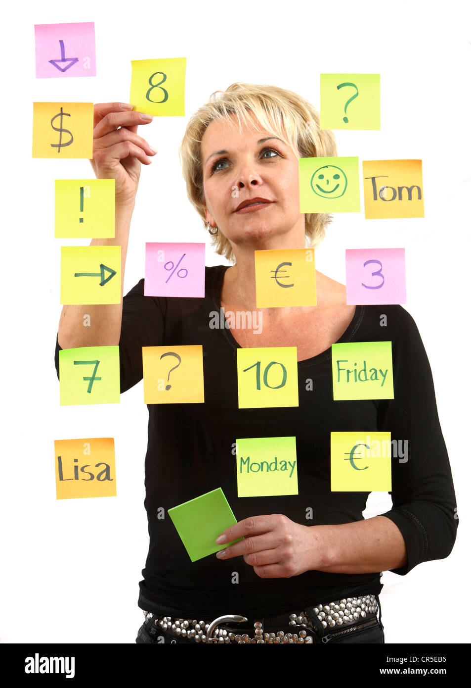 Frau klebt selbstklebenden Post-It, Notizen auf Papier, auf einer Glasscheibe geklebt. Verschiedenen Farben. Stockfoto