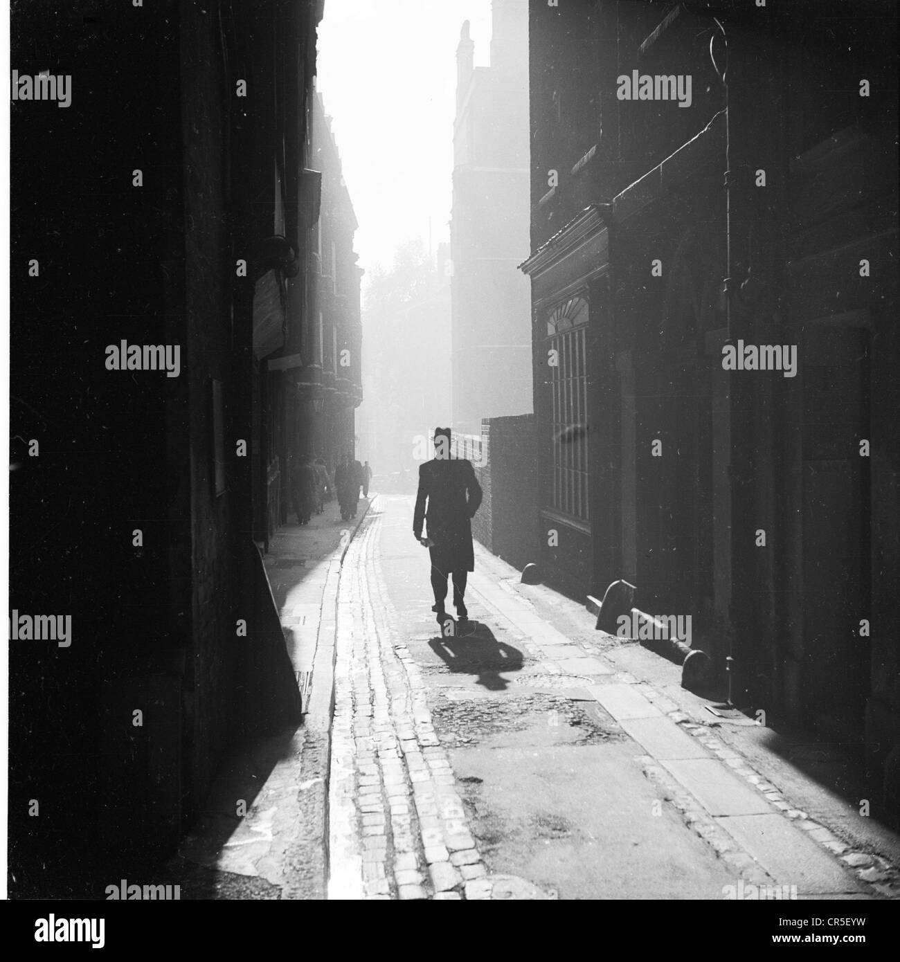 London, 1950er Jahre. Geschichtsbild, ein Stadt-Gentleman zu Fuß entlang einer dunklen Seitengasse von Tudor Altbauten hinter Staple Inn, High Holborn, beginnt so leicht entstehen. Stockfoto