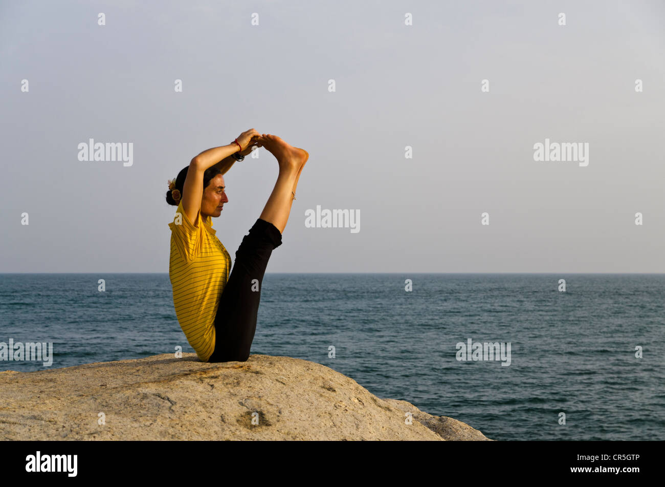 Frau in einem Yoga zu positionieren, eine Variation des Paschimothanasana, direkt am Meer in Kanyakumari, Tamil Nadu, Indien, Asien Stockfoto