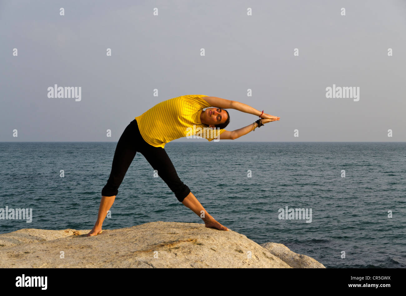 Frau in einem Yoga-position, Trikonasana, direkt am Meer in Kanyakumari, Tamil Nadu, Indien, Asien Stockfoto