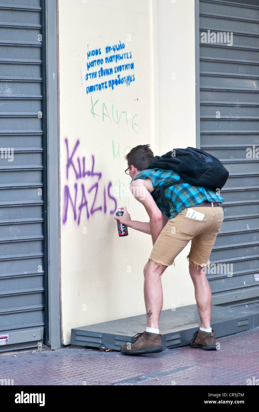 Anti-Nazi-Graffiti. Kerl mit Spray an der Wand "Kill Nazis" schreiben Stockfoto