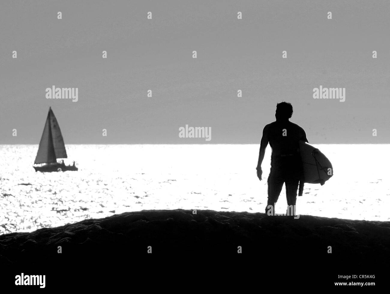 Surfer blickt auf das Meer bei Sonnenuntergang am Venice Beach, Kalifornien, Juli 2003. Stockfoto