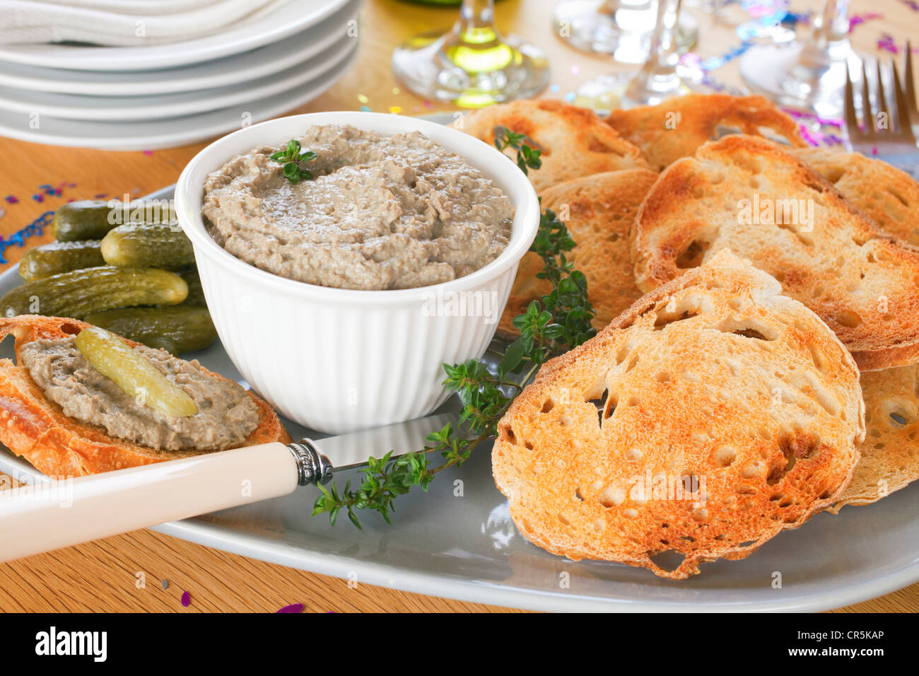 Hausgemachte Chicken Leber Pastete mit geröstetem Sauerteig und Cornichons, auf einer Platte angeordnet. Stockfoto