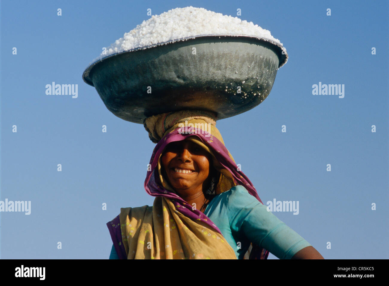 Frau, die eine große Schüssel mit Salz gefüllt auf dem Kopf, Malya, Gujarat, Indien, Asien Stockfoto