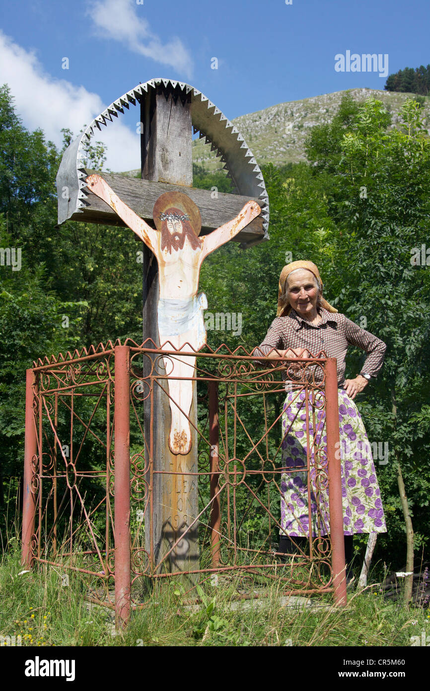 Alte Bäuerin stand neben einem Kruzifix, Rumänien, Europa Stockfoto