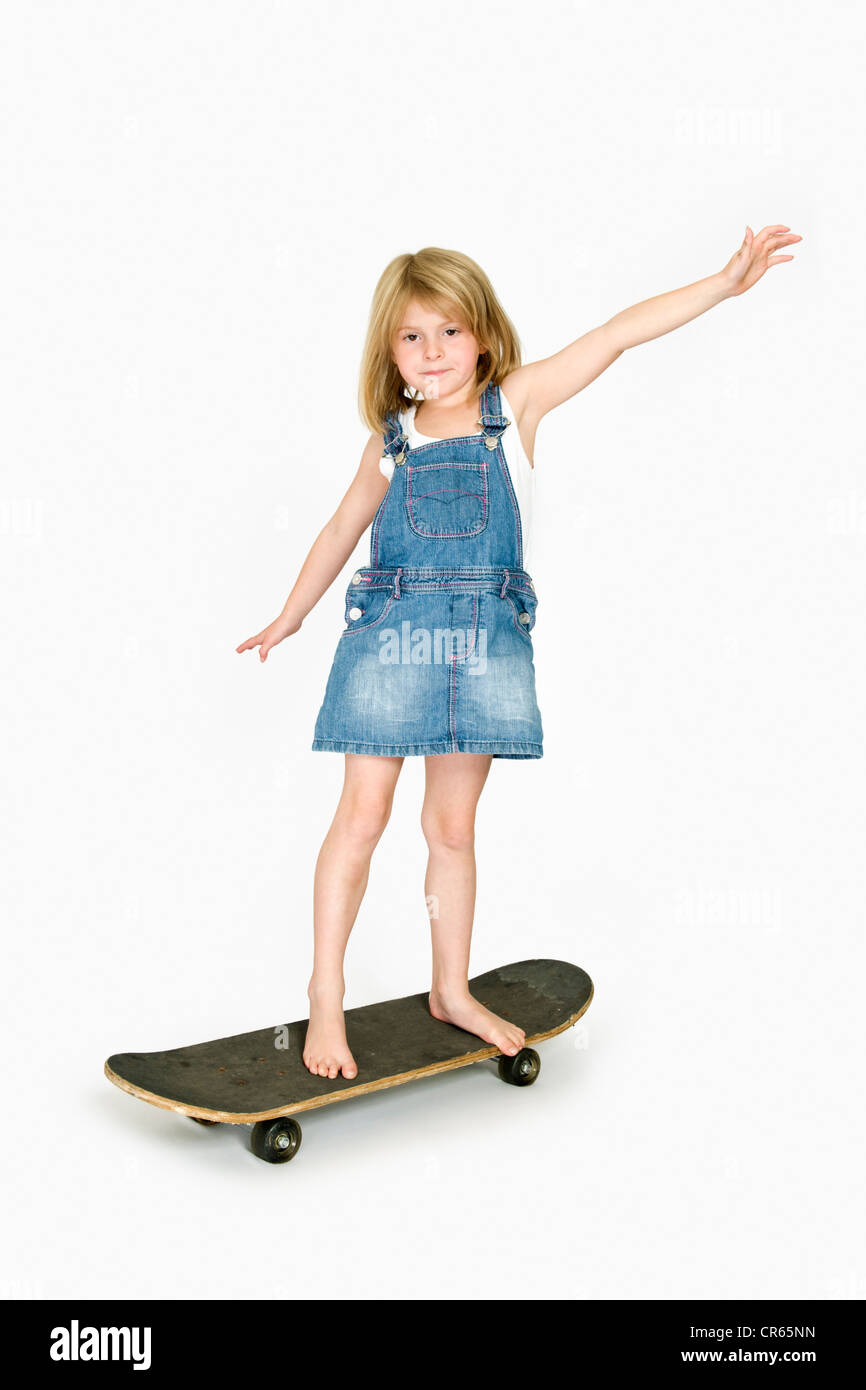 Studio Bild des kaukasischen 7 Jahre altes Mädchen in Jeansbekleidung mit Skateboard auf weißem Hintergrund mit Armen Stockfoto