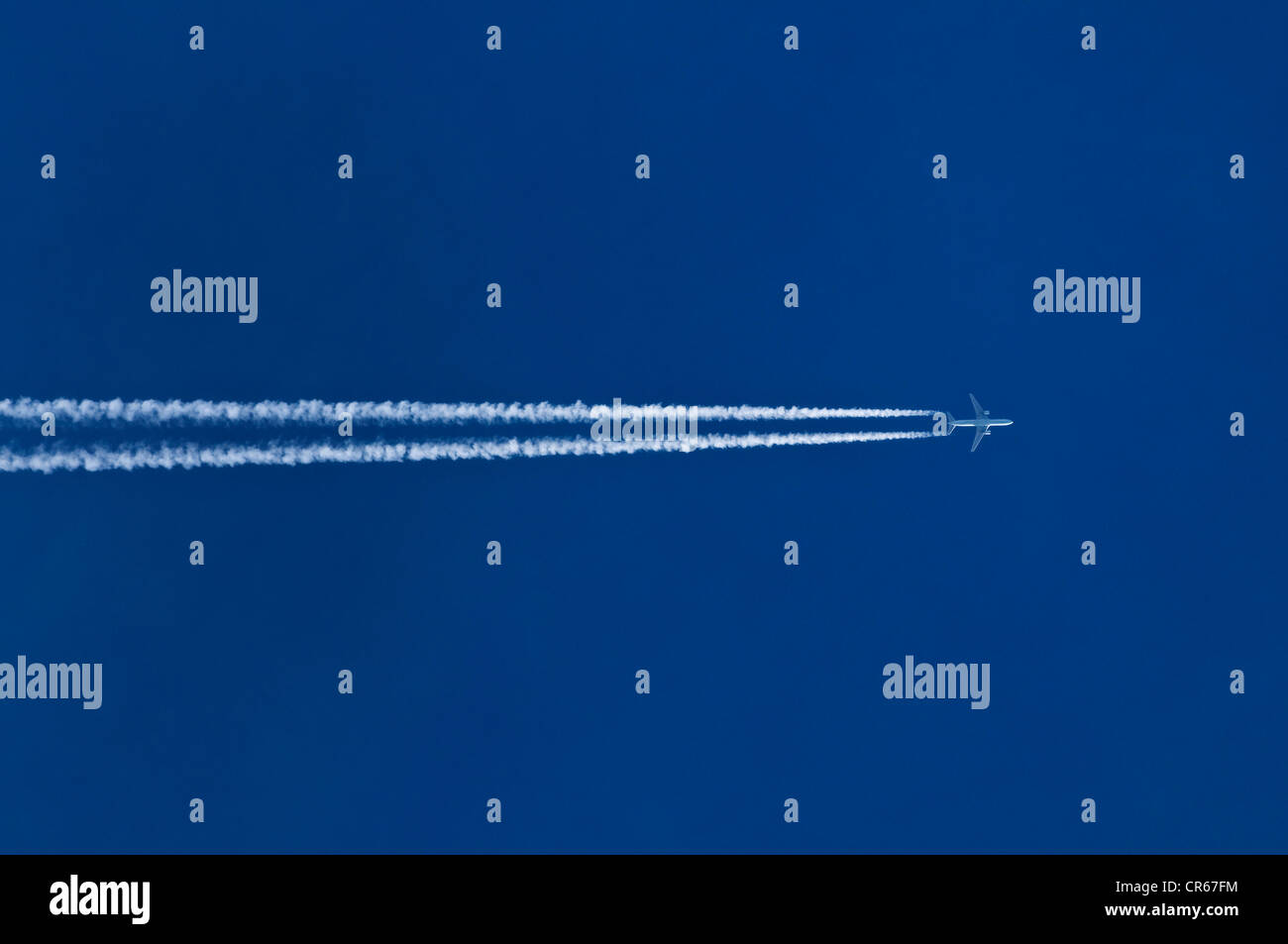 Doppelte Kondensstreifen hinter Flugzeug in den blauen Himmel Stockfoto