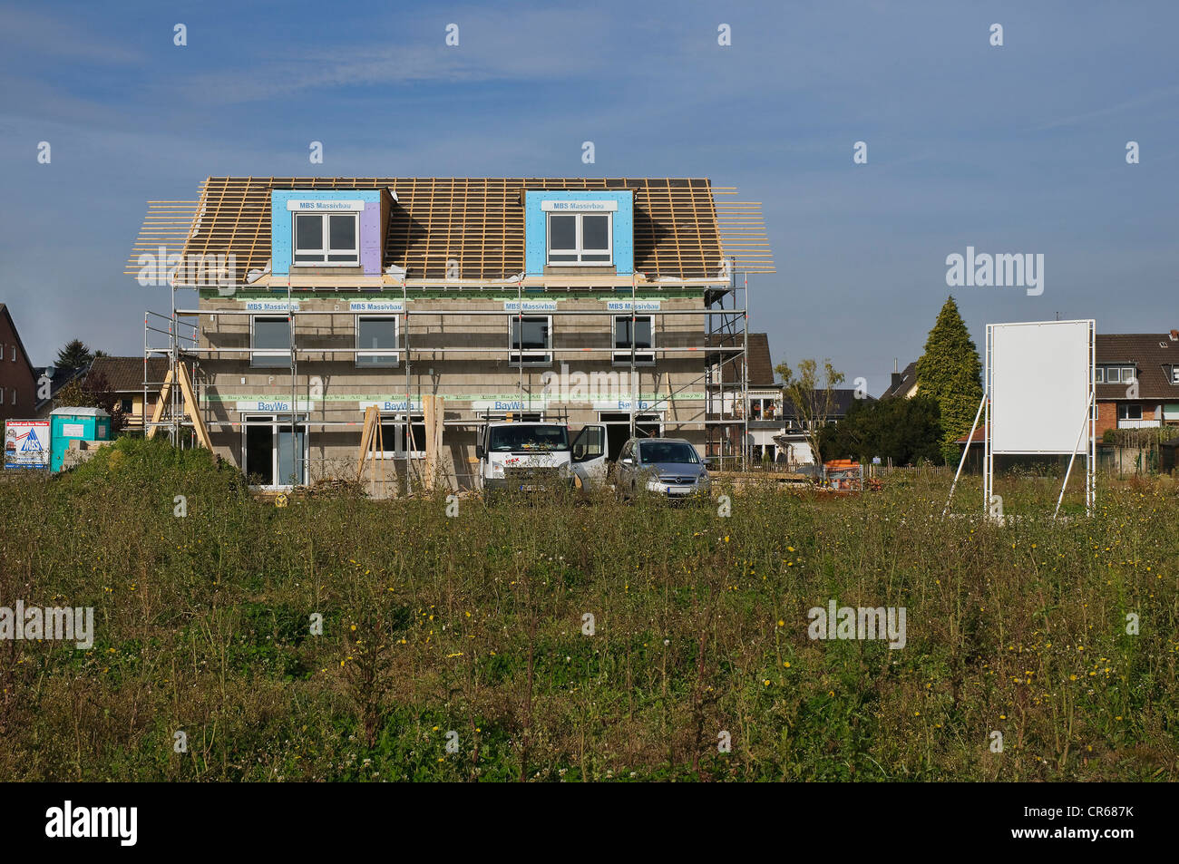 Baugebiet, Mehrfamilienhaus, umgeben von Gerüsten mit Sparren, kurz bevor Dach gefliest werden Stockfoto