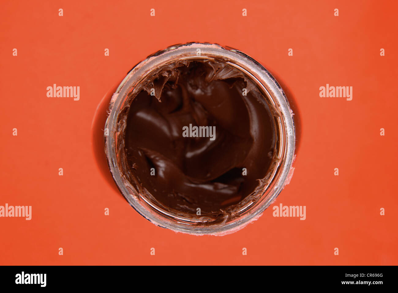 Glas mit Nuss Schokolade Creme auf orangem Hintergrund, Nahaufnahme Stockfoto