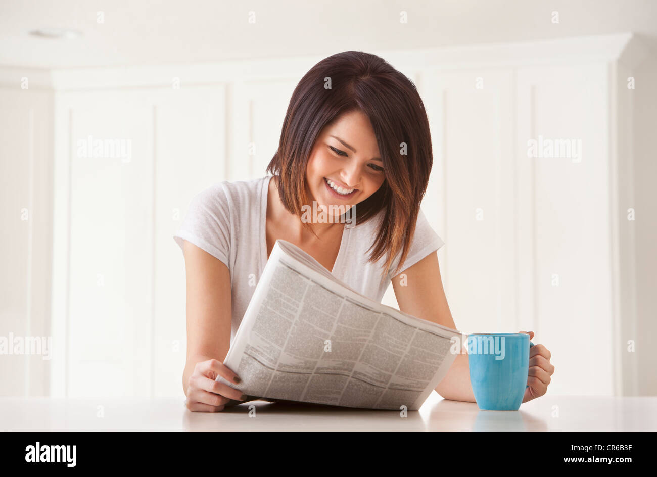 Junge Frau mit Zeitung und Becher Stockfoto