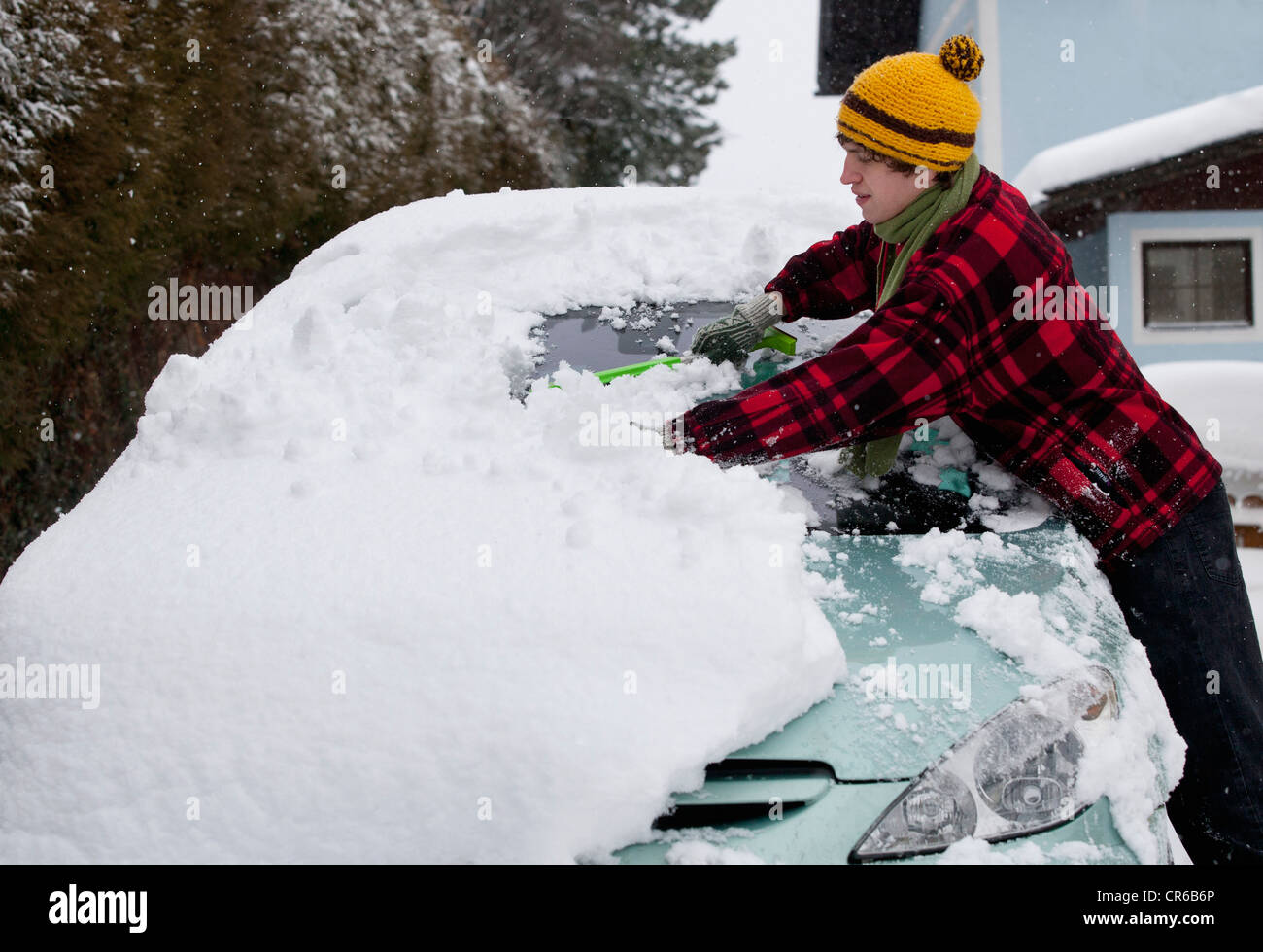 Österreich, junge Mann Reinigung Schnee auf dem Auto Stockfoto