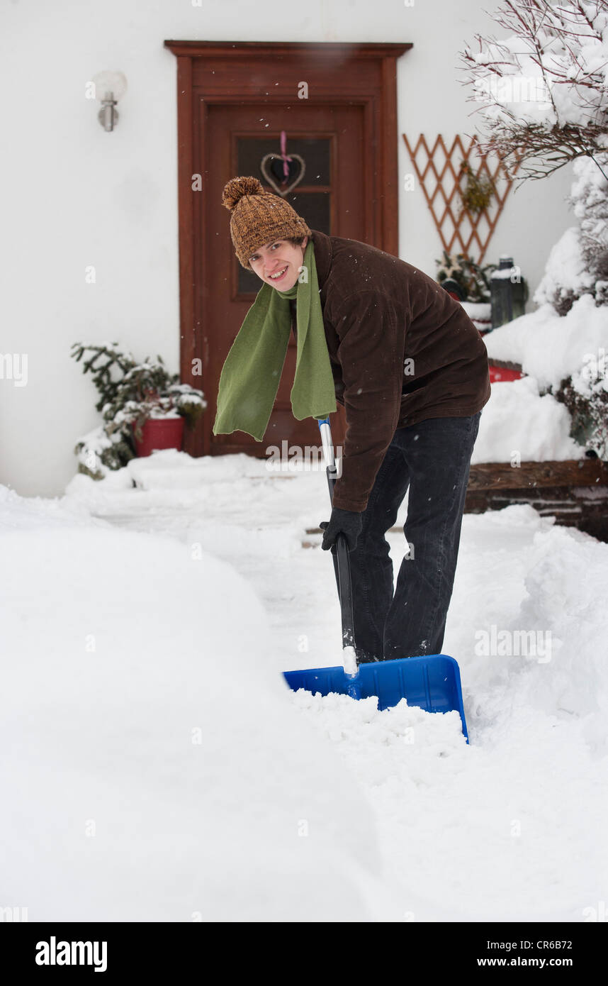Österreich, junger Mann Schaufeln Schnee vor Haus, Porträt Stockfoto