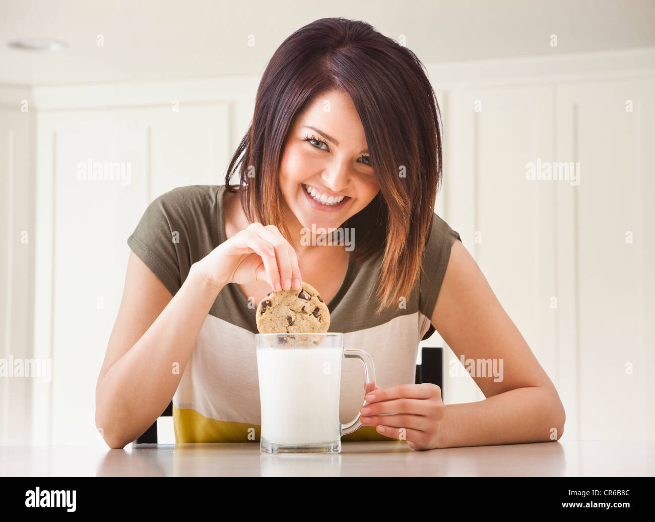 Junge Frau Keks mit Milch zu essen Stockfoto