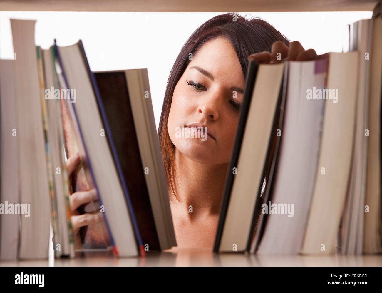 Porträt der jungen Frau Suche Buch im Regal Stockfoto