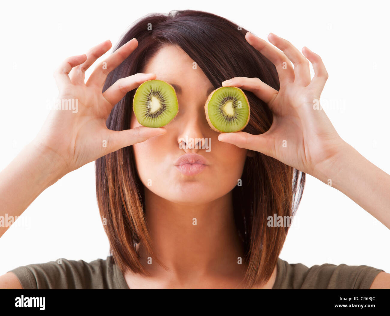 Junge Frau mit Kiwi-Scheiben auf Augen Stockfoto