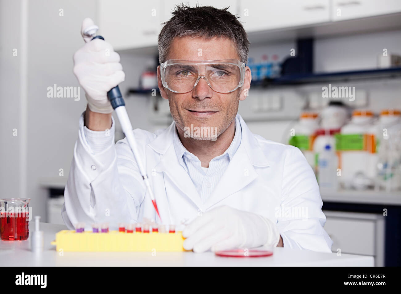 Deutschland, Bayern, München, Wissenschaftler strömenden rote Flüssigkeit mit Pipette im Reagenzglas für die medizinische Forschung im Labor Stockfoto