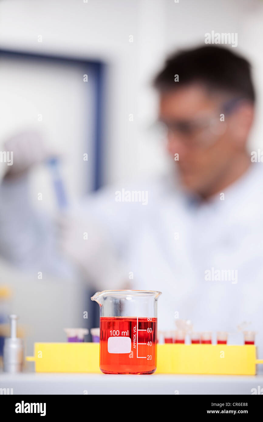 Deutschland, Bayern, München, rote Flüssigkeit im Becherglas, Wissenschaftler, die medizinische Forschung im Hintergrund Stockfoto