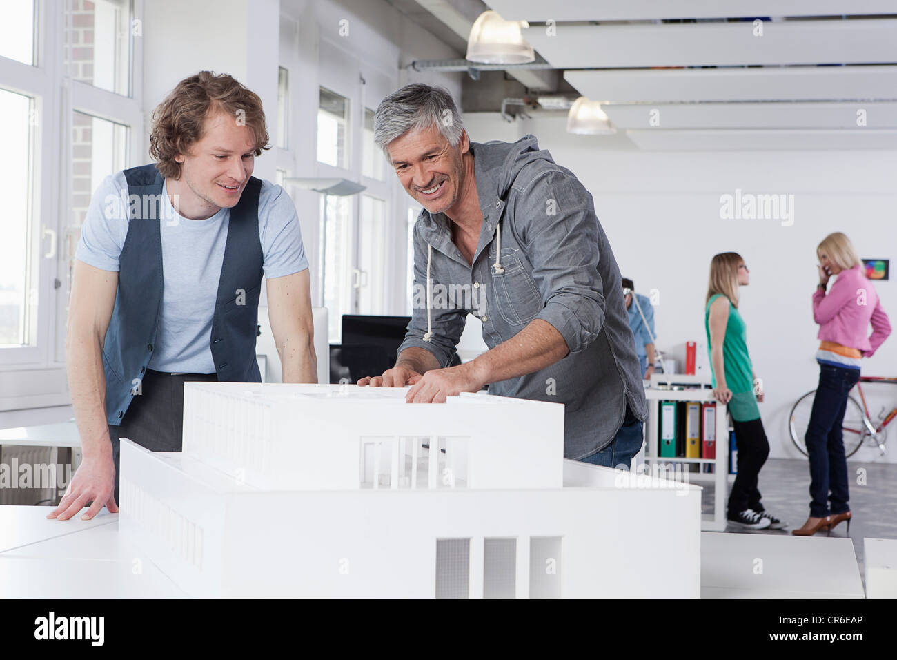 Deutschland, Bayern, München, Männer zusehen Architekturmodell in Büro, Kollegen reden im Hintergrund Stockfoto