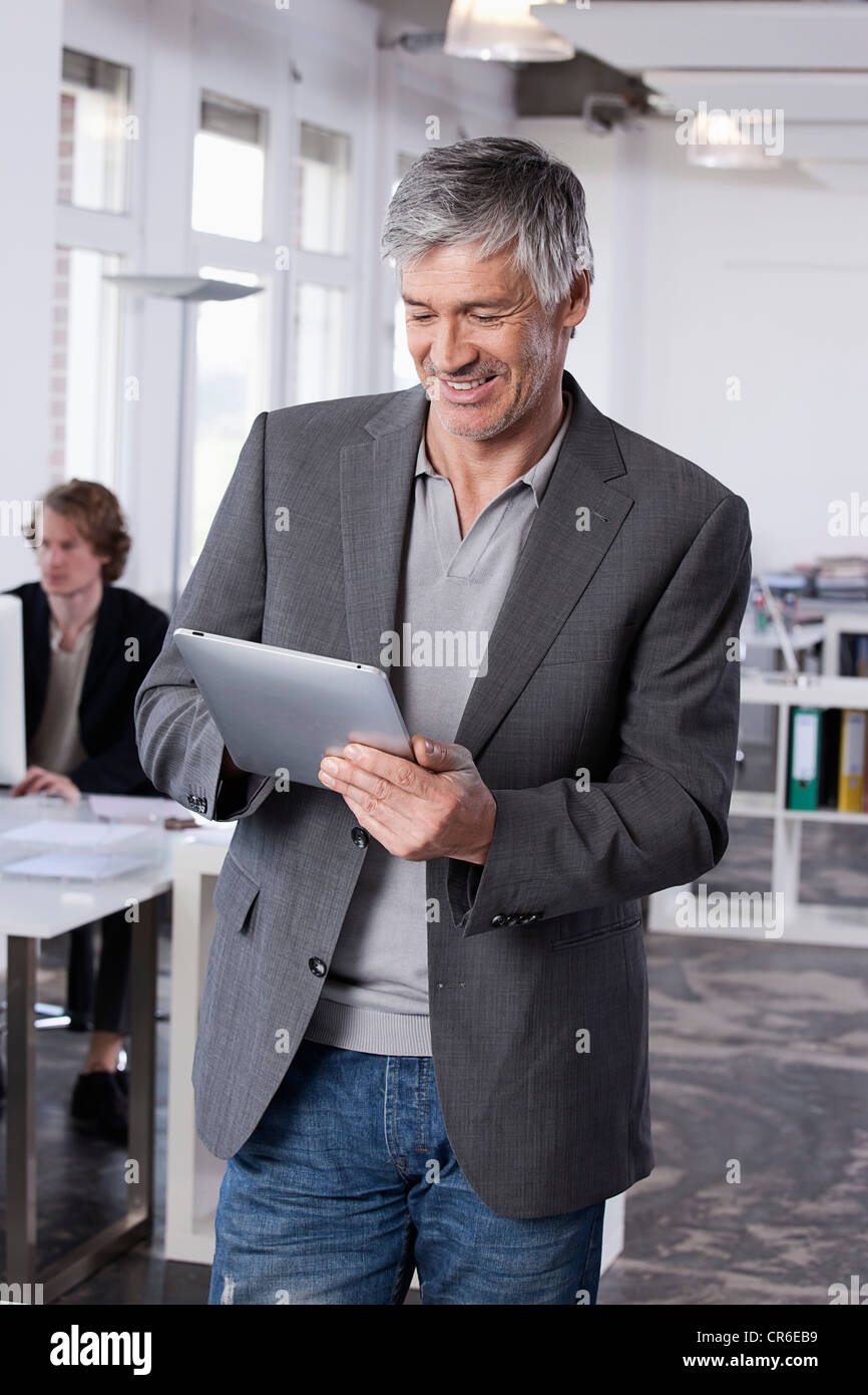 Deutschland, Bayern, München, reifer Mann mit digital-Tablette, Kollege arbeitet im Hintergrund Stockfoto