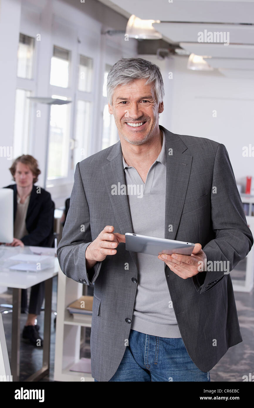Deutschland, Bayern, München, reifer Mann mit digital-Tablette, Kollege arbeitet im Hintergrund Stockfoto