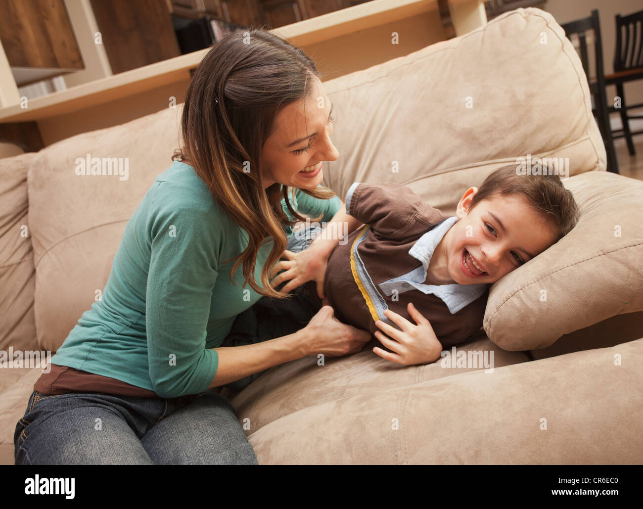 Mutter kitzeln ihres Sohnes (6-7) auf couch Stockfoto