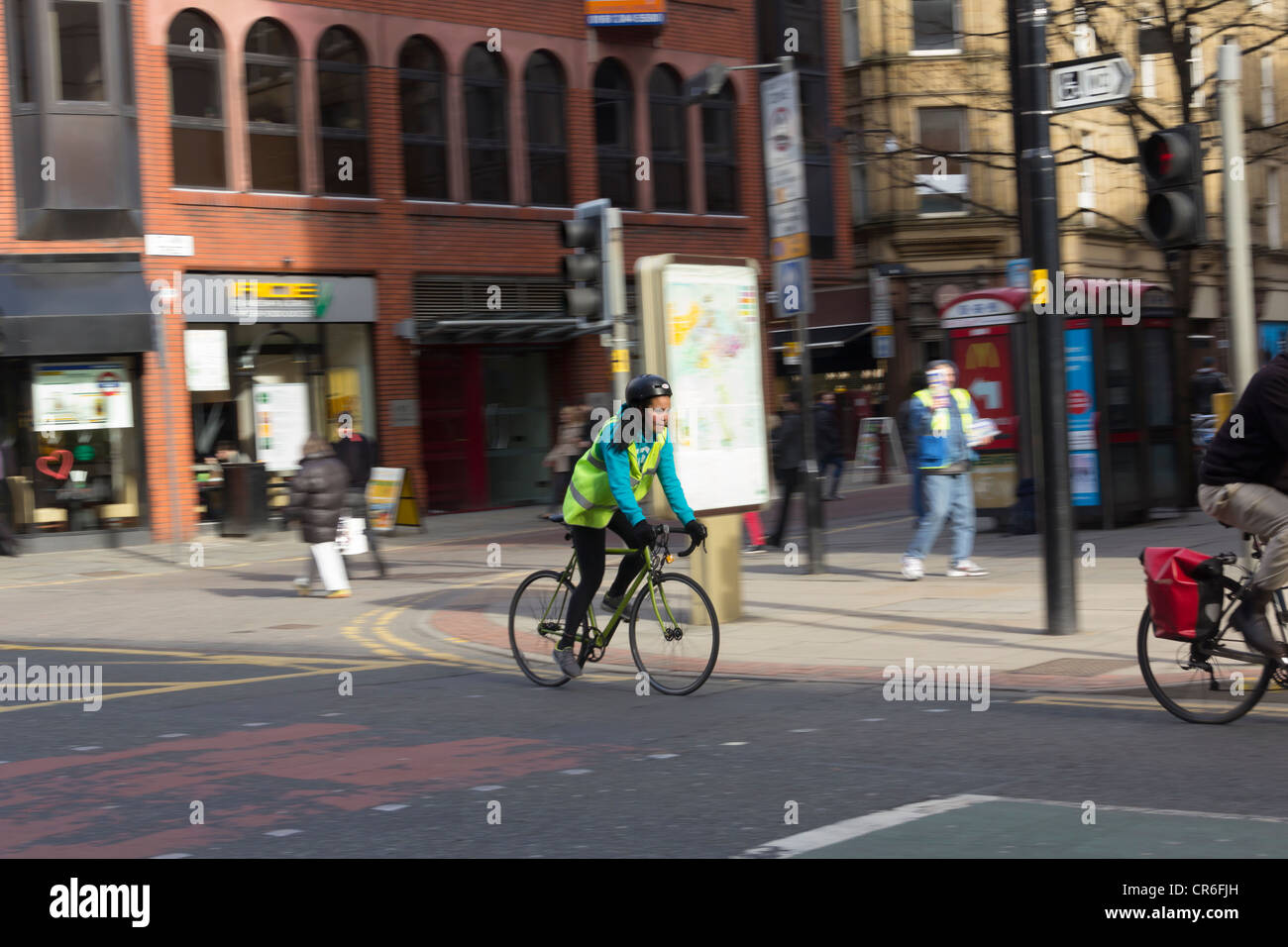 Junge weibliche Radfahrer am Deansgate, Manchester. Sie ist eine reflektierende Warnweste hi-Vis, Handschuhe und einen Fahrradhelm tragen. Stockfoto