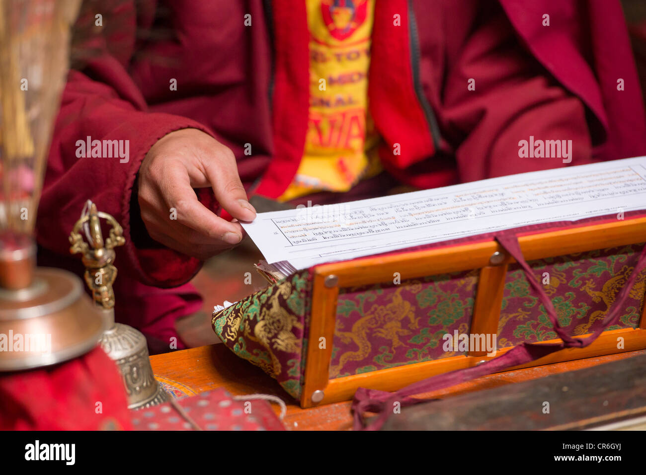 Mönch lesen aus Gebetbuch in der Gebetsraum im Hemis Gompa, (Ladakh) Jammu & Kaschmir, Indien Stockfoto