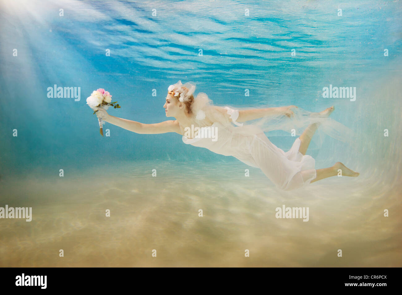 Kaukasische Braut im Hochzeitskleid Schwimmen unter Wasser Stockfoto