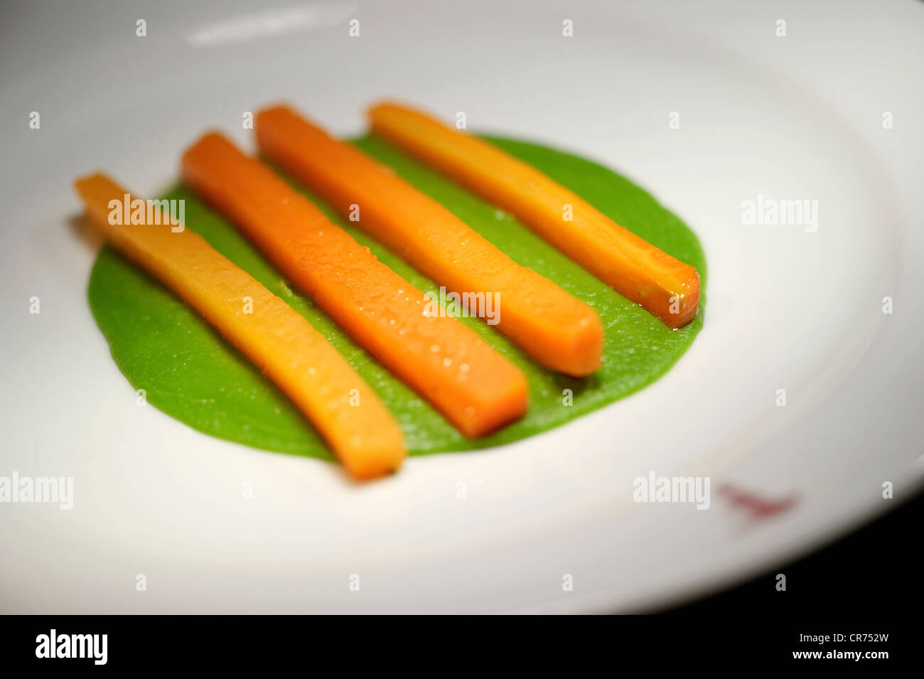 gehackte Karotte steckt in Linien auf einem Bett aus Erbsenpüree auf einem weißen Teller in einem restaurant Stockfoto