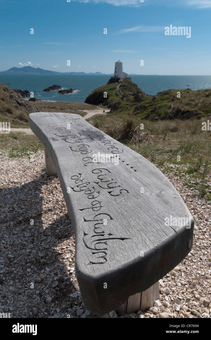 Geschnitzte Holzsitz mit Blick auf den alten Leuchtturm und Lleyn-Halbinsel auf Llanddwyn Insel Anglesey North Wales Stockfoto