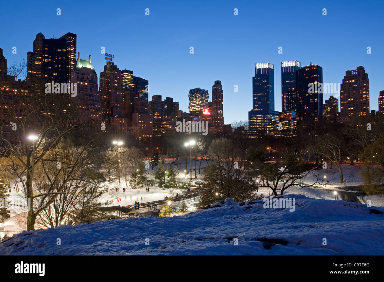 Vereinigte Staaten, New York City, Manhattan, Central Park im Winter unter dem Schnee, Eis, Eislaufbahn Wollman Rink und die Türme von Midtown Stockfoto