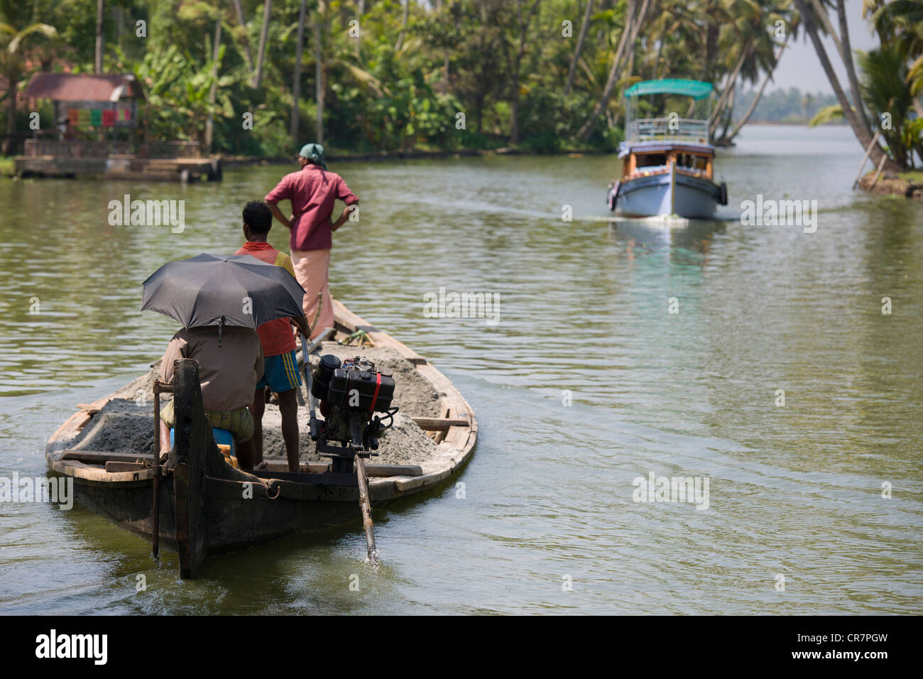 Touristenboot nähert sich einem überladenen Lastkahn in einem Wasserweg der Vattakayal See in der Nähe von Alappuzha (Alleppey), Kerala, Indien Stockfoto