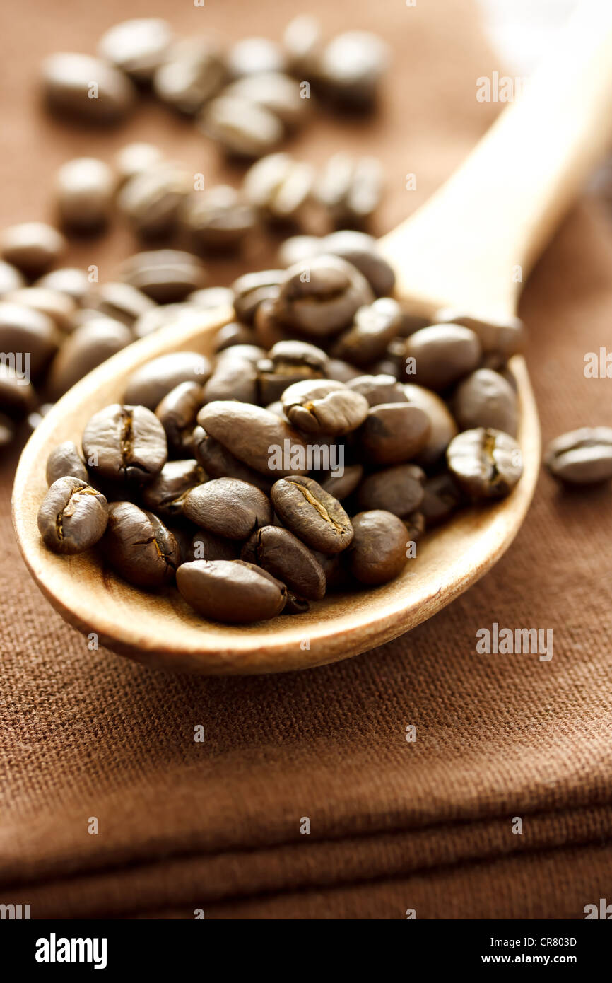 Kaffeebohnen in Holzlöffel auf braunem Tuch Stockfoto