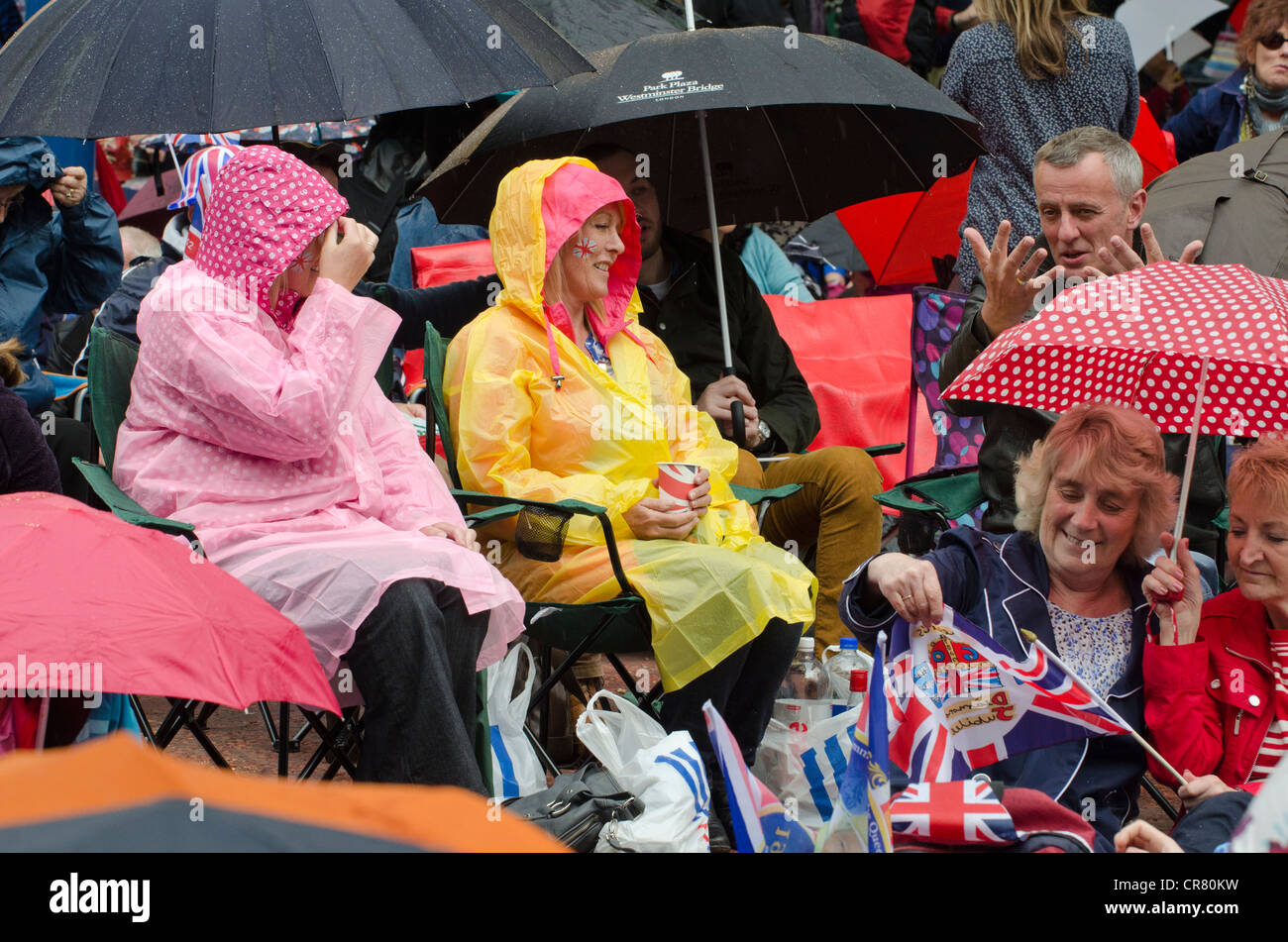 Regen durchnässt Nachtschwärmer bei der Königin Diamond Jubilee warten auf Pop-Konzert in der Mall. Sonnenschirme, und Regenbekleidung. Stockfoto