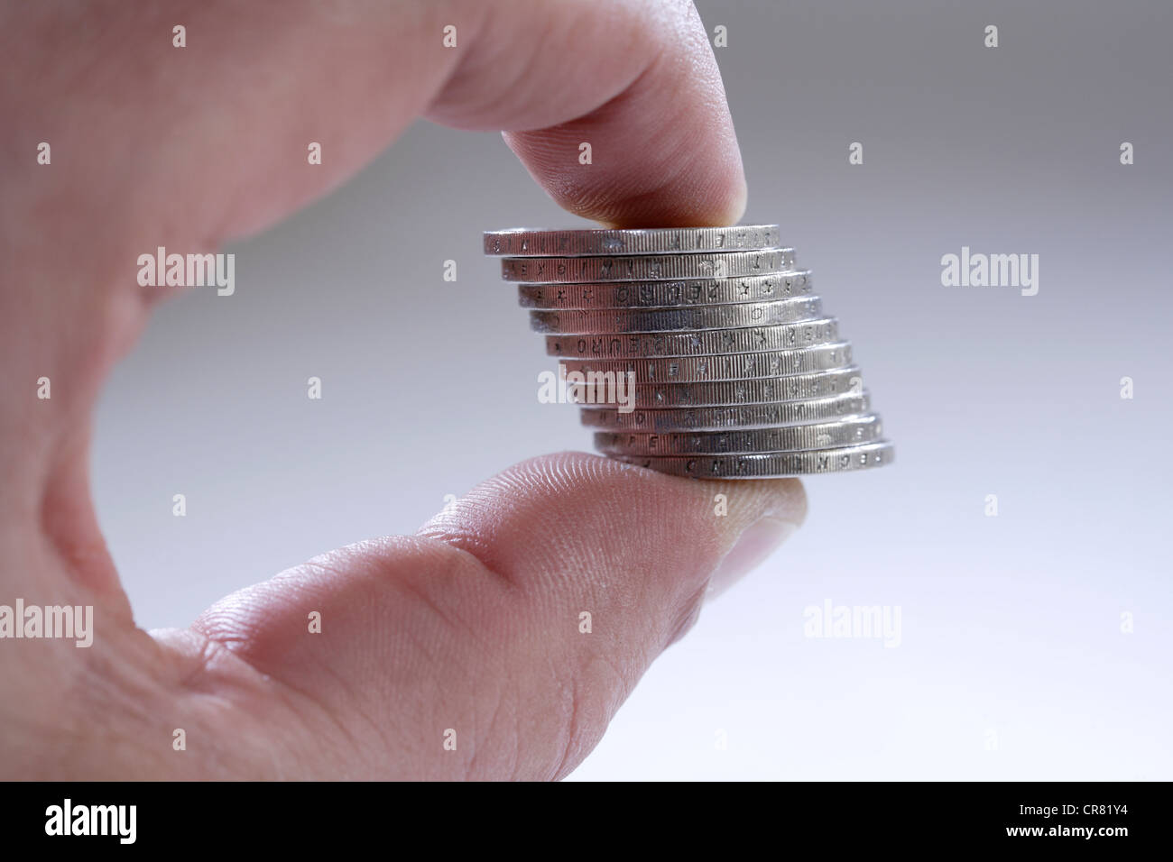 Haufen von Euro-Münzen zwischen Zeigefinger und Daumen Stockfoto