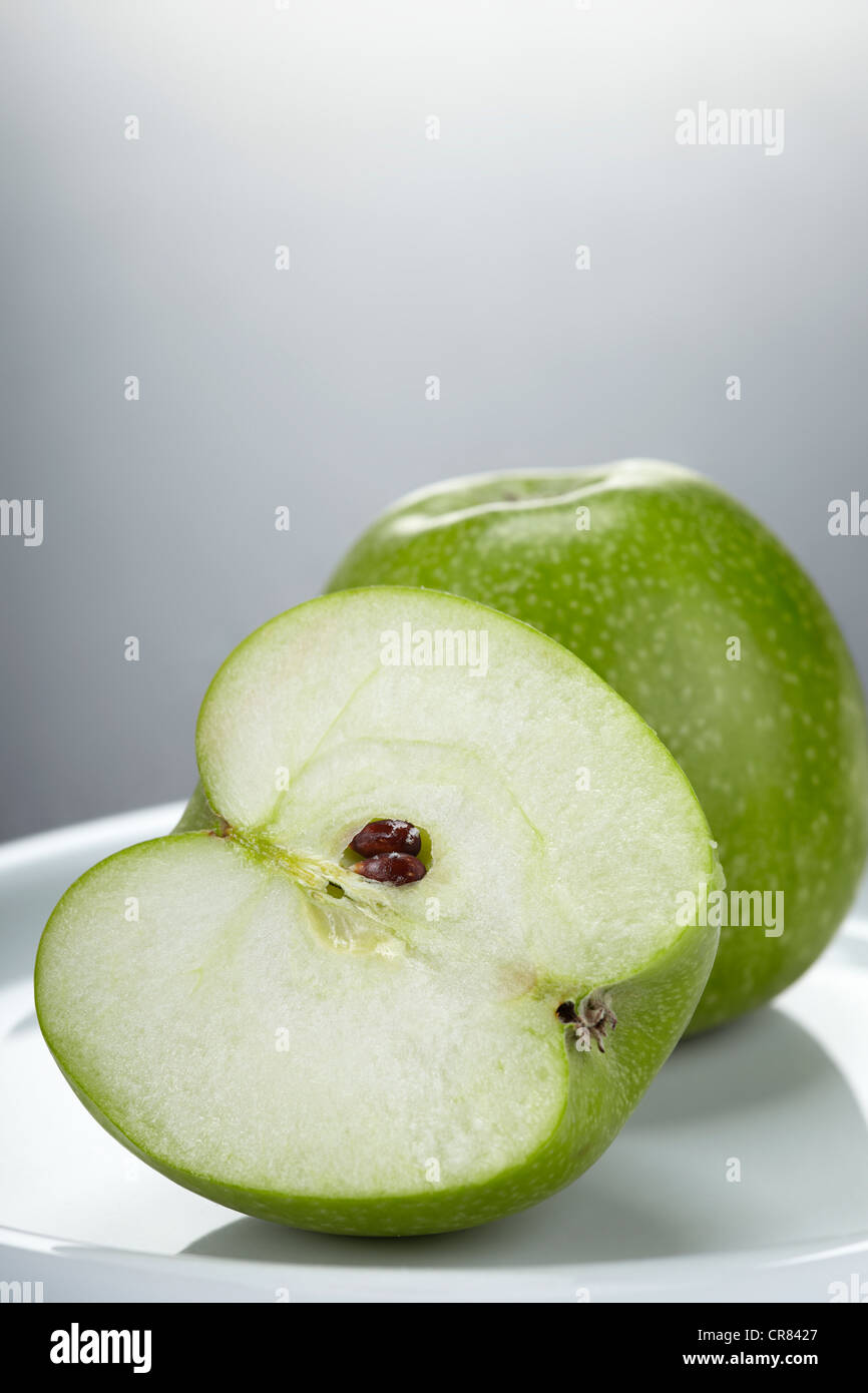 Zwei grüne Granny Smith Äpfel, einen ganzen Apfel und einen Apfel in zwei Hälften geschnitten Stockfoto