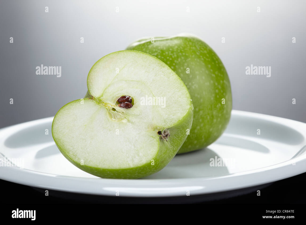 Zwei grüne Granny Smith Äpfel aufgeschnitten eine, auf einem weißen Teller Stockfoto