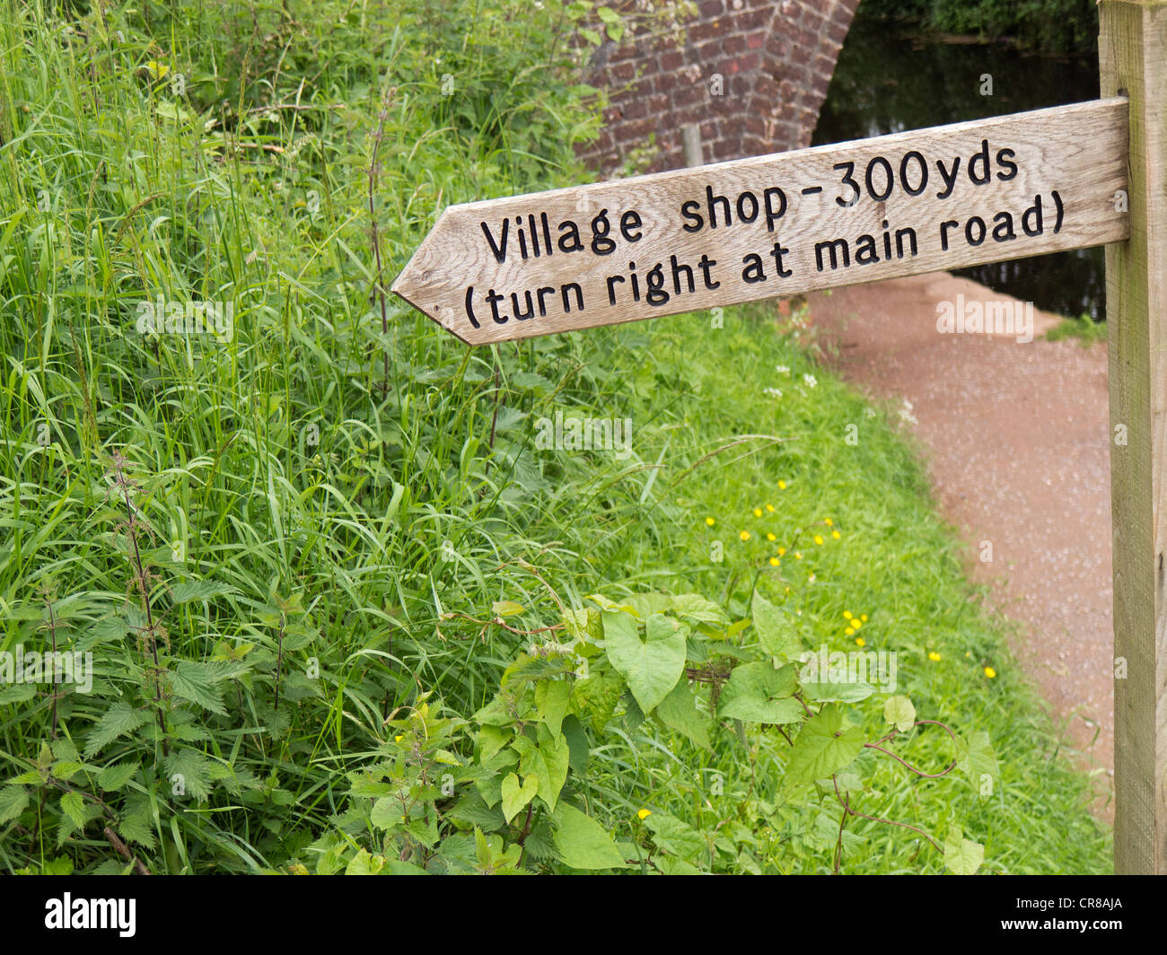 Wegweiser zu den lokalen Dorfladen aus einem Kanal Leinpfad. Stockfoto