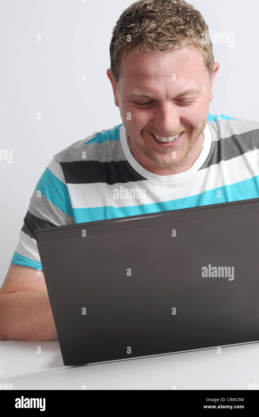 Studioaufnahme des Jünglings mit Notebook gegen die graue Wand. Stockfoto