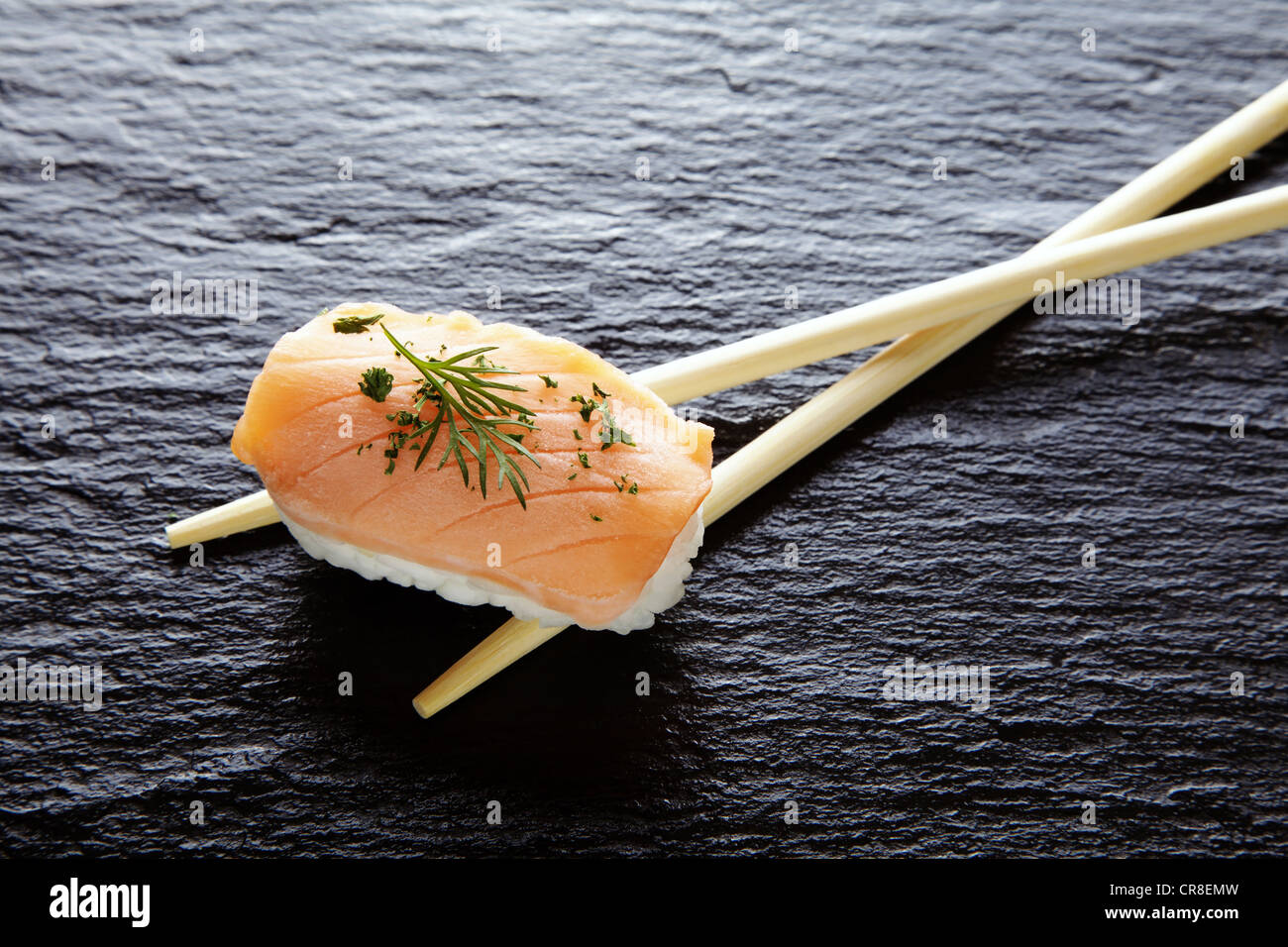 Sushi, Nigiri mit Lachs und Stäbchen auf eine Schieferoberfläche Stockfoto